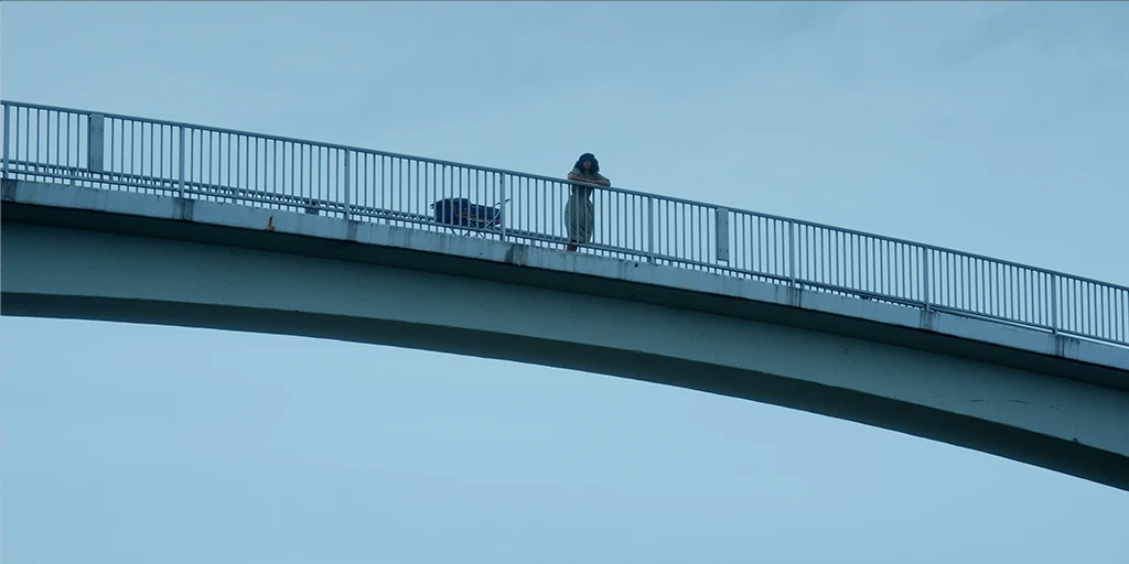 Die Protagonistin des Films »Die Mathematik der Dinge« steht in bläulicher Atmosphäre auf einer Brücke und betrachtet die Landschaft