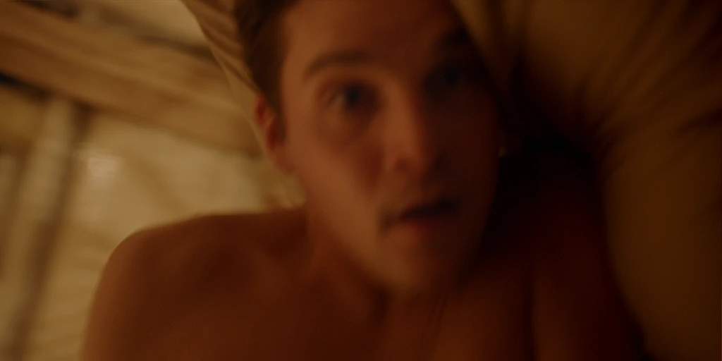 In einer warmen Atmosphäre schaut der Protagonist (Benjamin Lillie) in seinem Bett erleichtert in die Kamera und fällt seitlich in die Kissen im Werbespot »True Romance«.