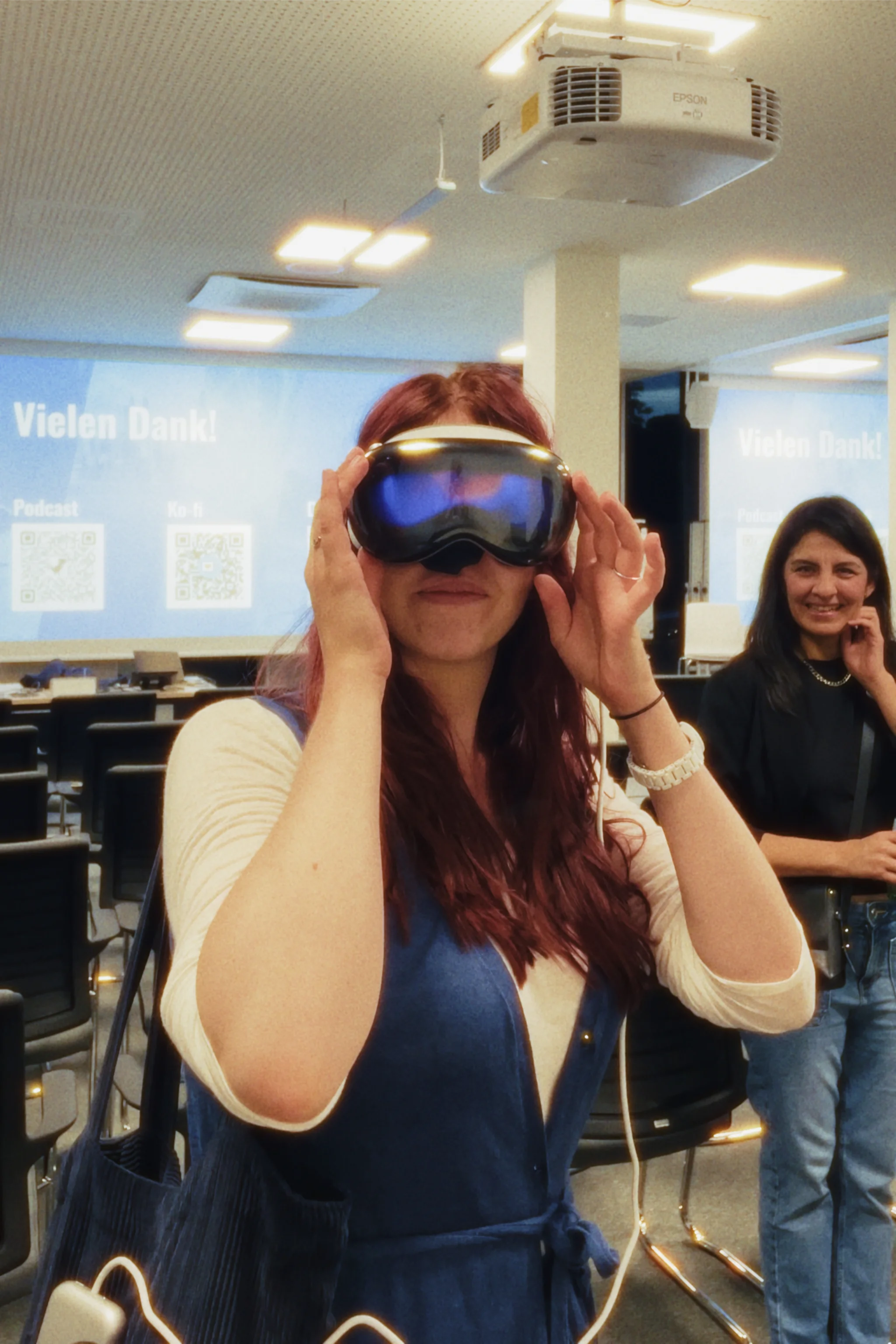 Eine Frau mit roten Haaren schaut durch eine Apple Vision Pro. © Johannes Schmülling